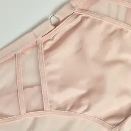 Figi Omena to wyjątkowa propozycja dla kobiet ceniących elegancję, komfort i subtelną zmysłowość. Model wykonany jest z miękkiego, przyjemnego dla skóry materiału, który doskonale dopasowuje się do sylwetki i zapewnia wygodę przez cały dzień.
Boki majtek zostały ozdobione transparentnymi panelami z delikatnej siateczki, które nadają całości lekkości oraz kobiecego charakteru. Centralny element z przodu uzupełnia niewielki ozdobny detal, podkreślający elegancki design modelu.
Pudrowy, cielisty odcień sprawia, że figi są niezwykle uniwersalne i idealnie sprawdzą się zarówno na co dzień, jak i jako element bardziej zmysłowego kompletu bielizny. Klasyczny krój zapewnia wygodne dopasowanie i pięknie podkreśla linię bioder.
85% Poliamid, 10% Elastan, 5% Poliester
To doskonały wybór dla kobiet, które szukają bielizny łączącej wygodę, estetykę i subtelną elegancję.
 